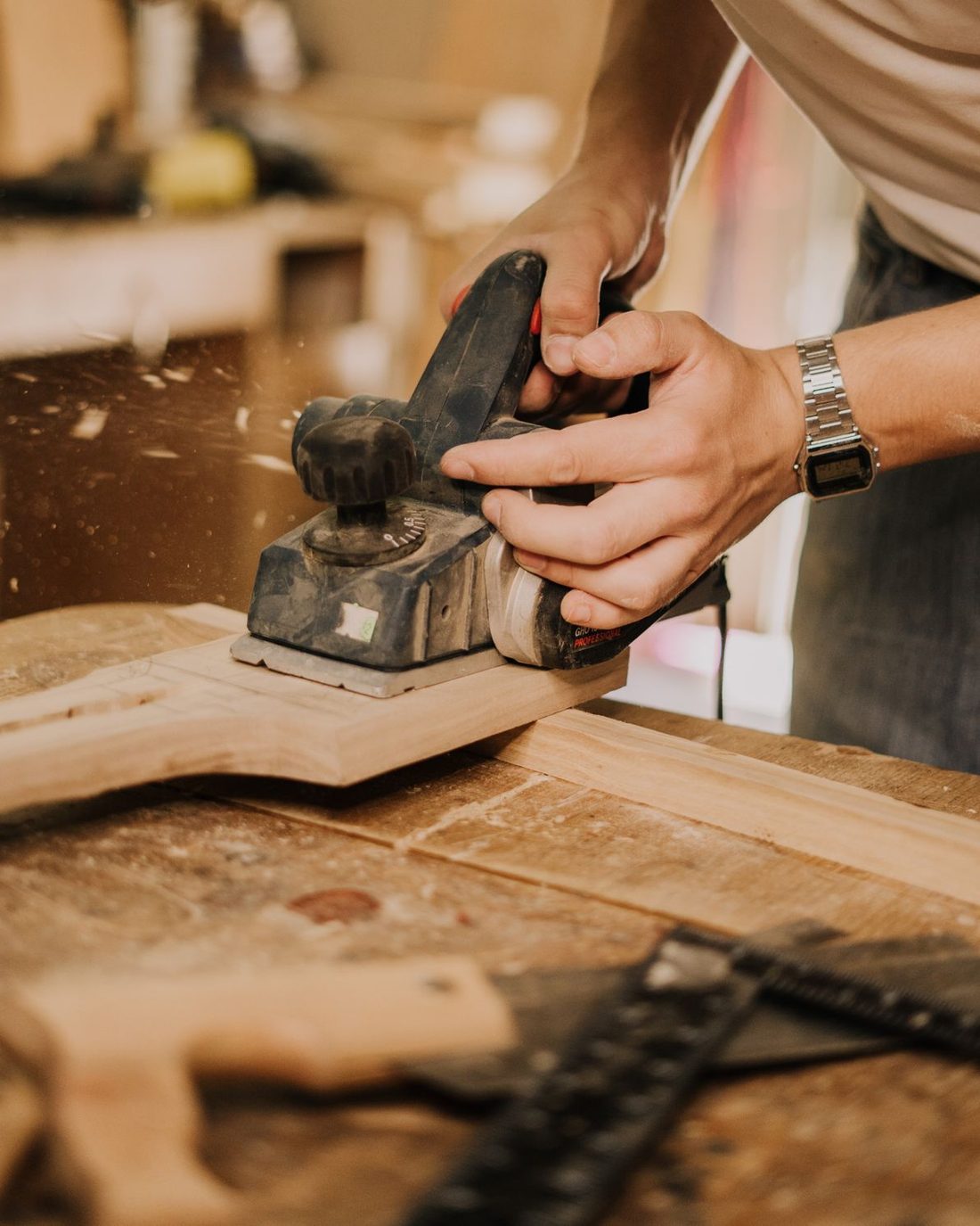 A carpenter planing a board smooth on a workbench