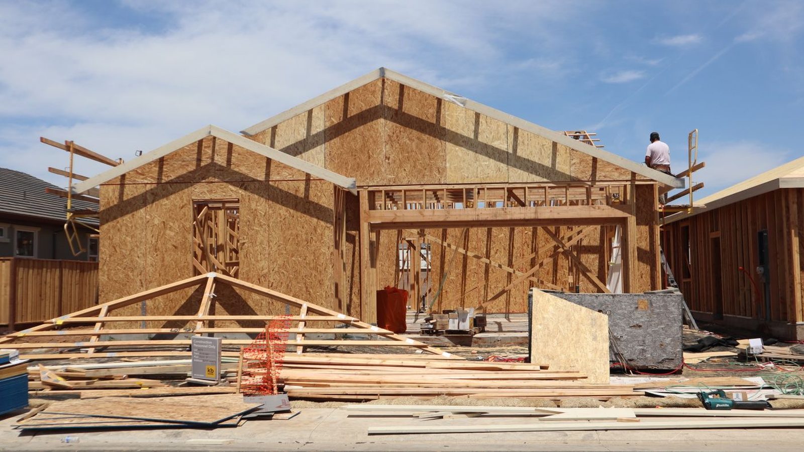 A new residential home under construction, framed and sheathed with roof trusses set
