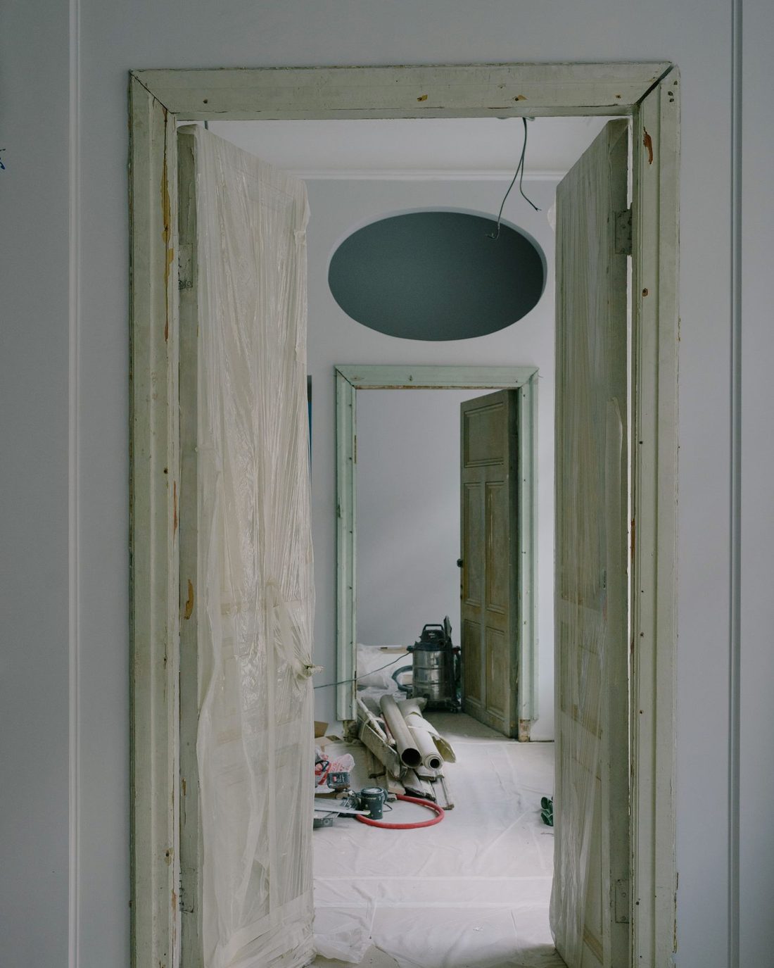 Interior of an older home mid-renovation, floors protected and doors removed